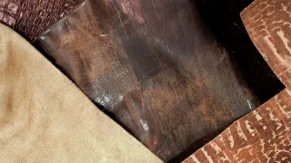Recortes de cuero de distinto tipo sobre una mesa: piel afelpada clara tipo venado, cuero liso oscuro y dos piezas con grabado de reptil